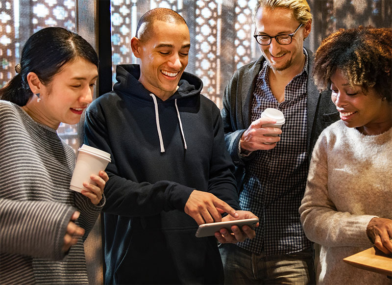 bunch of people smiling and looking at a tablet