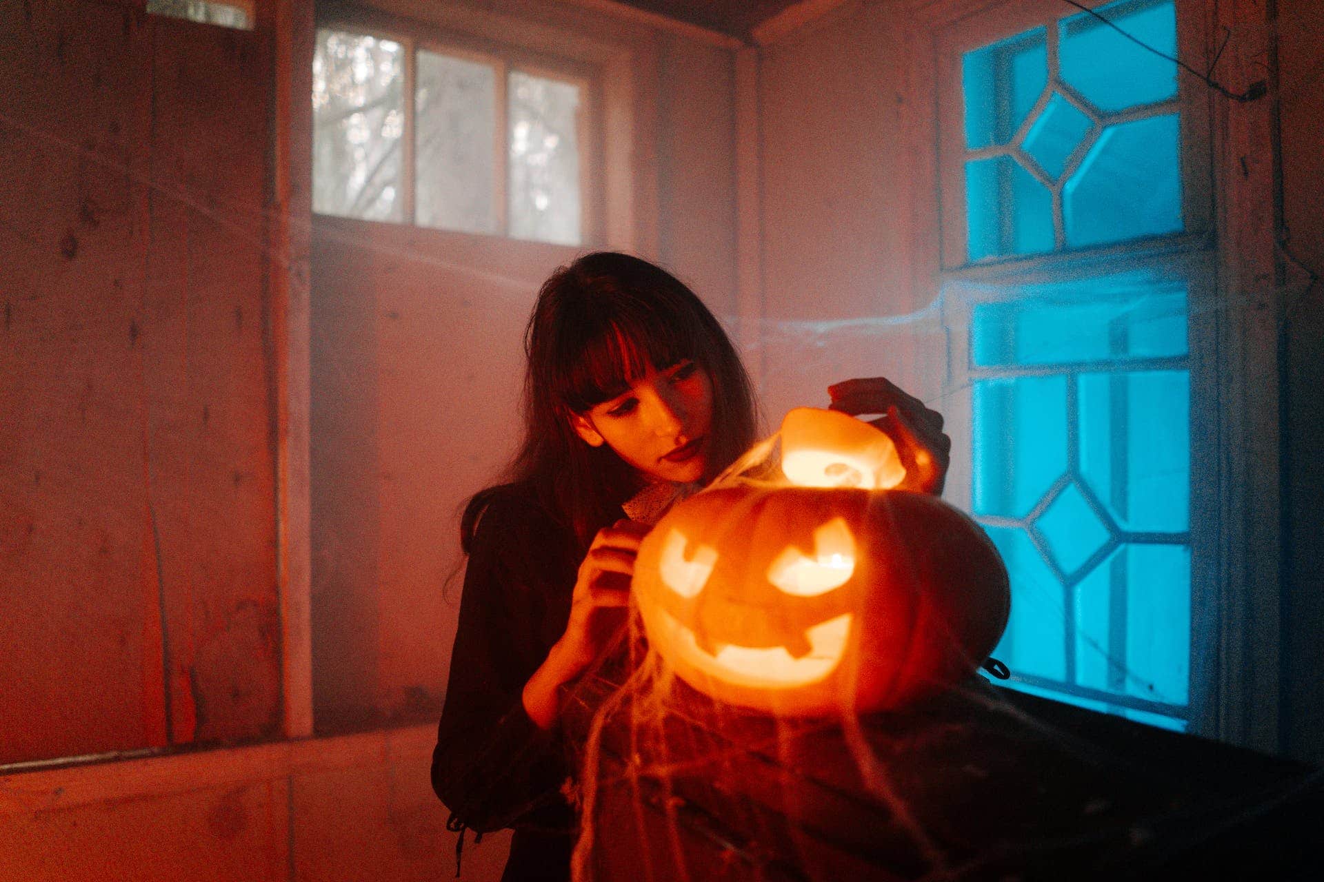 Woman lights spooky cobweb covered pumpkin