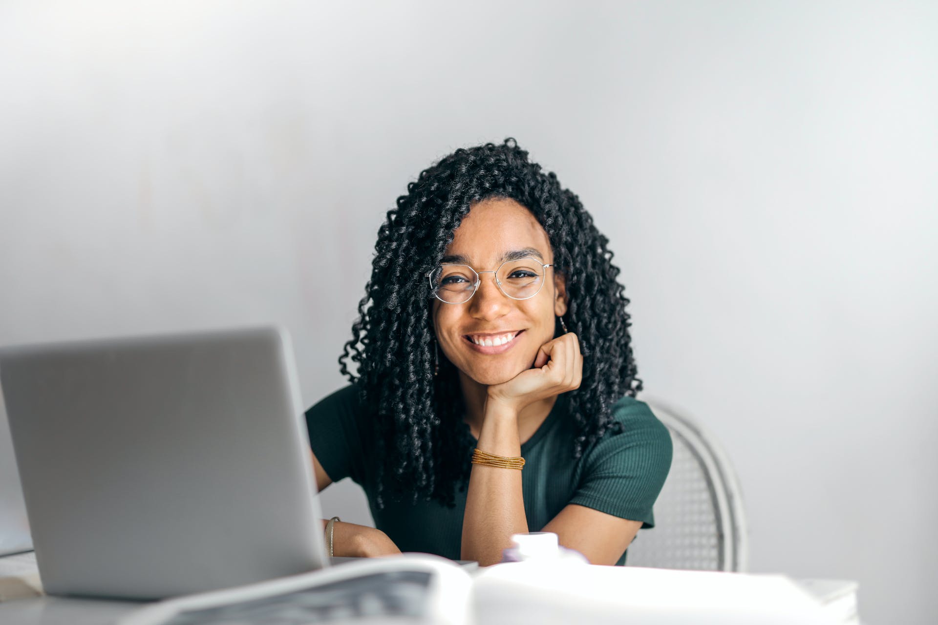 Smiling woman looking at camera while sitting behind laptop