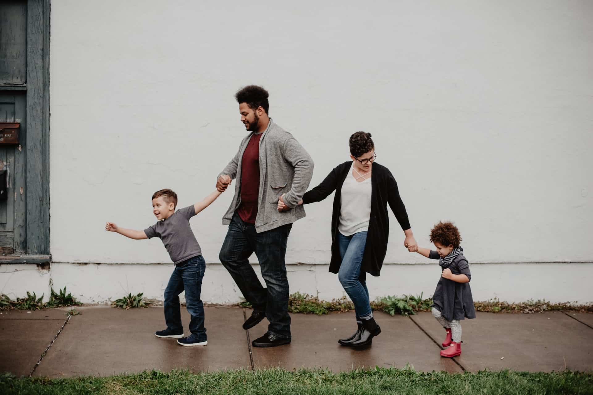 Family of four happily holding hands while walking on a wet sidewalk