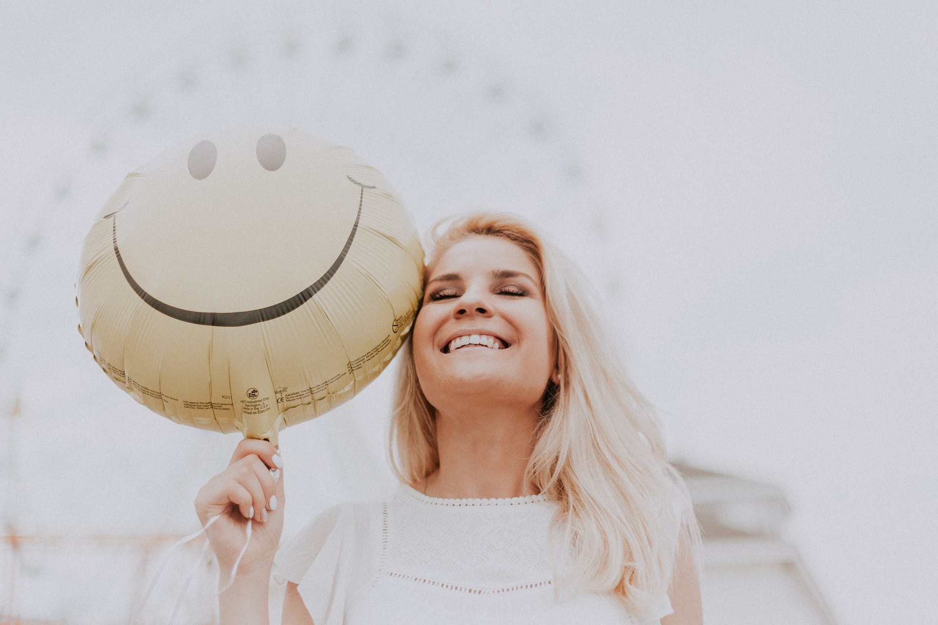 Woman smiling while holding a happy face balloon