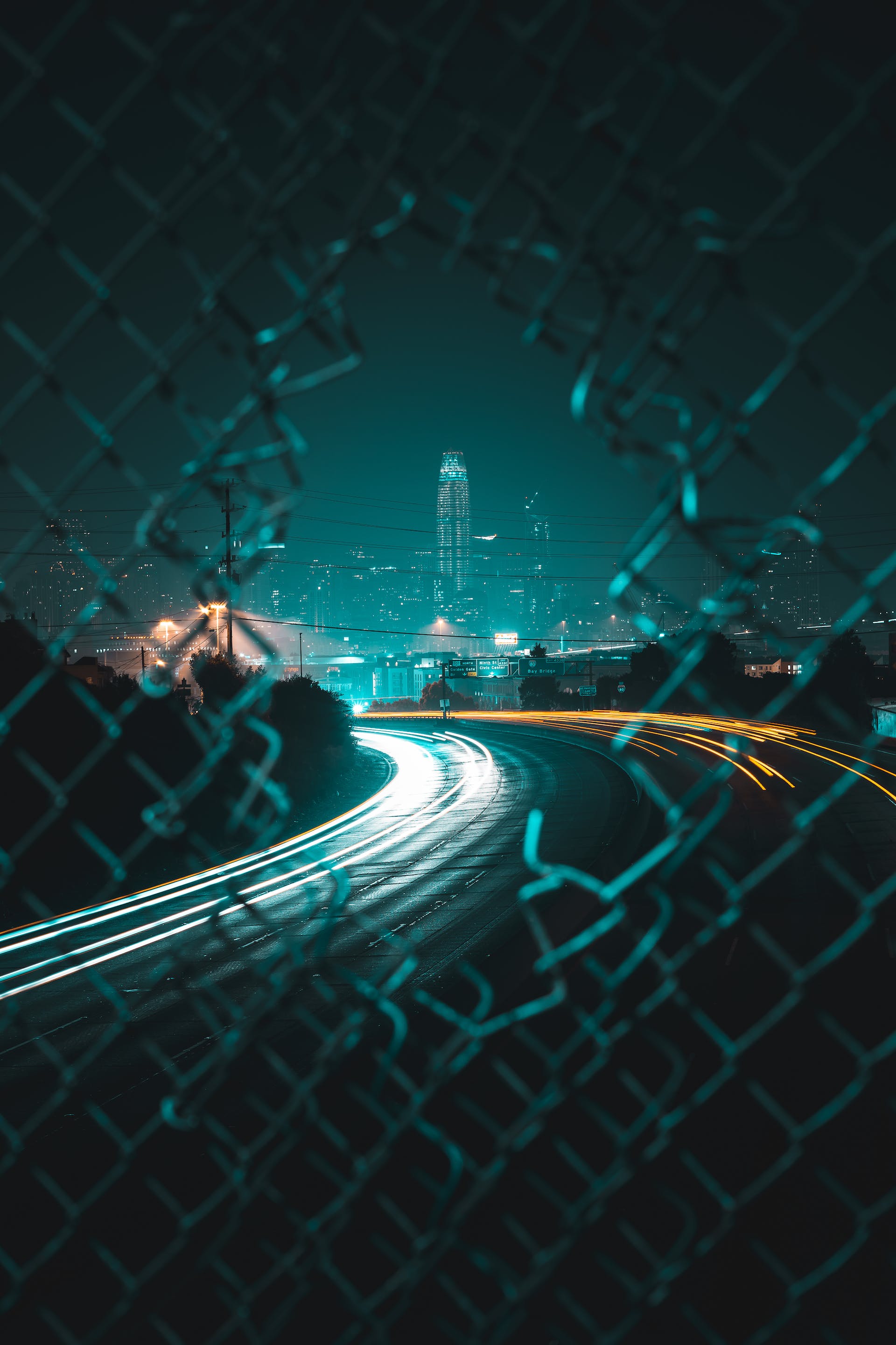 Image of the San Francisco skyline as seen through a hold in a chain link fence