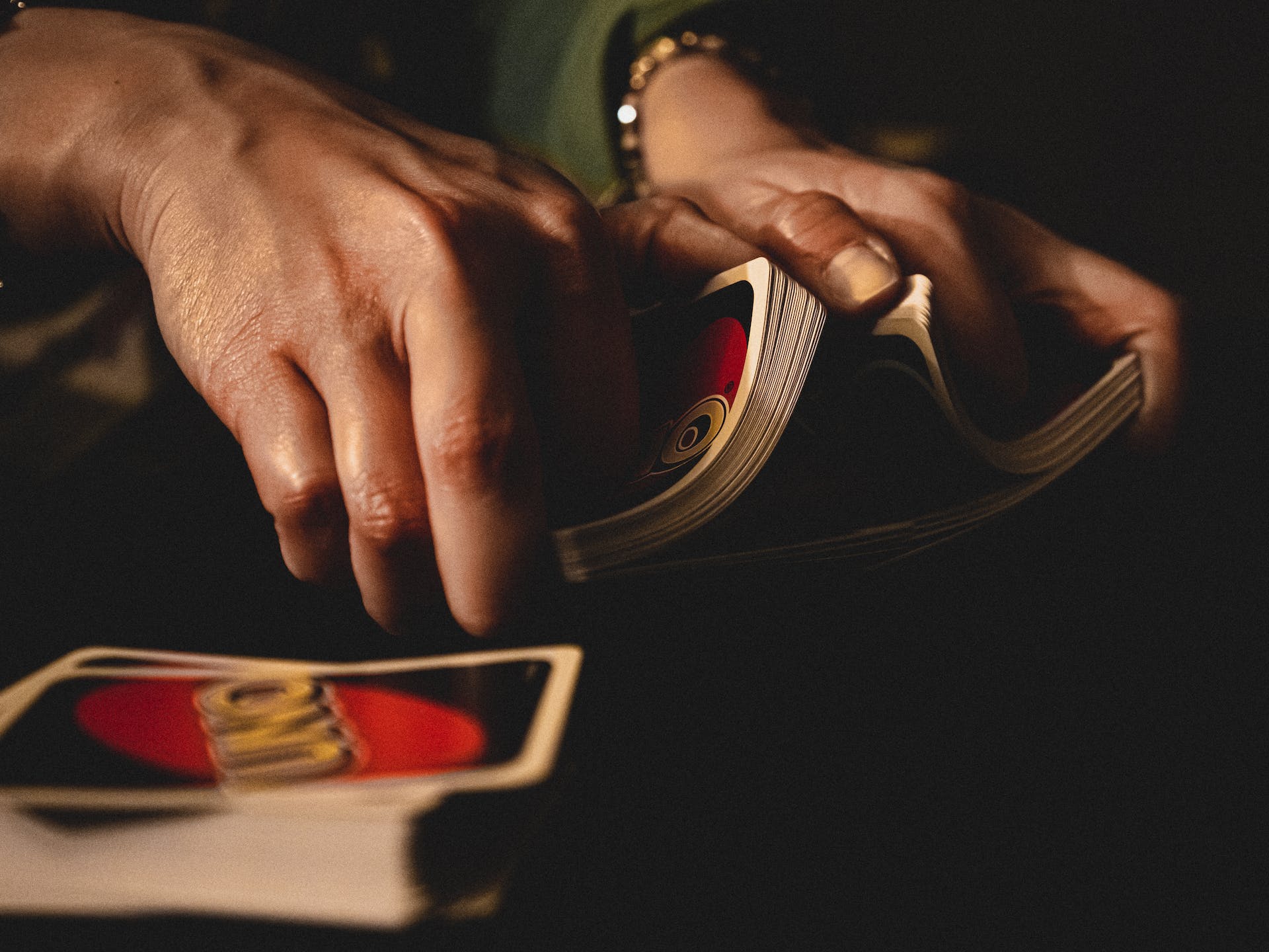 Hands shuffle Uno cards with a deck waiting too e shuffled in the foreground