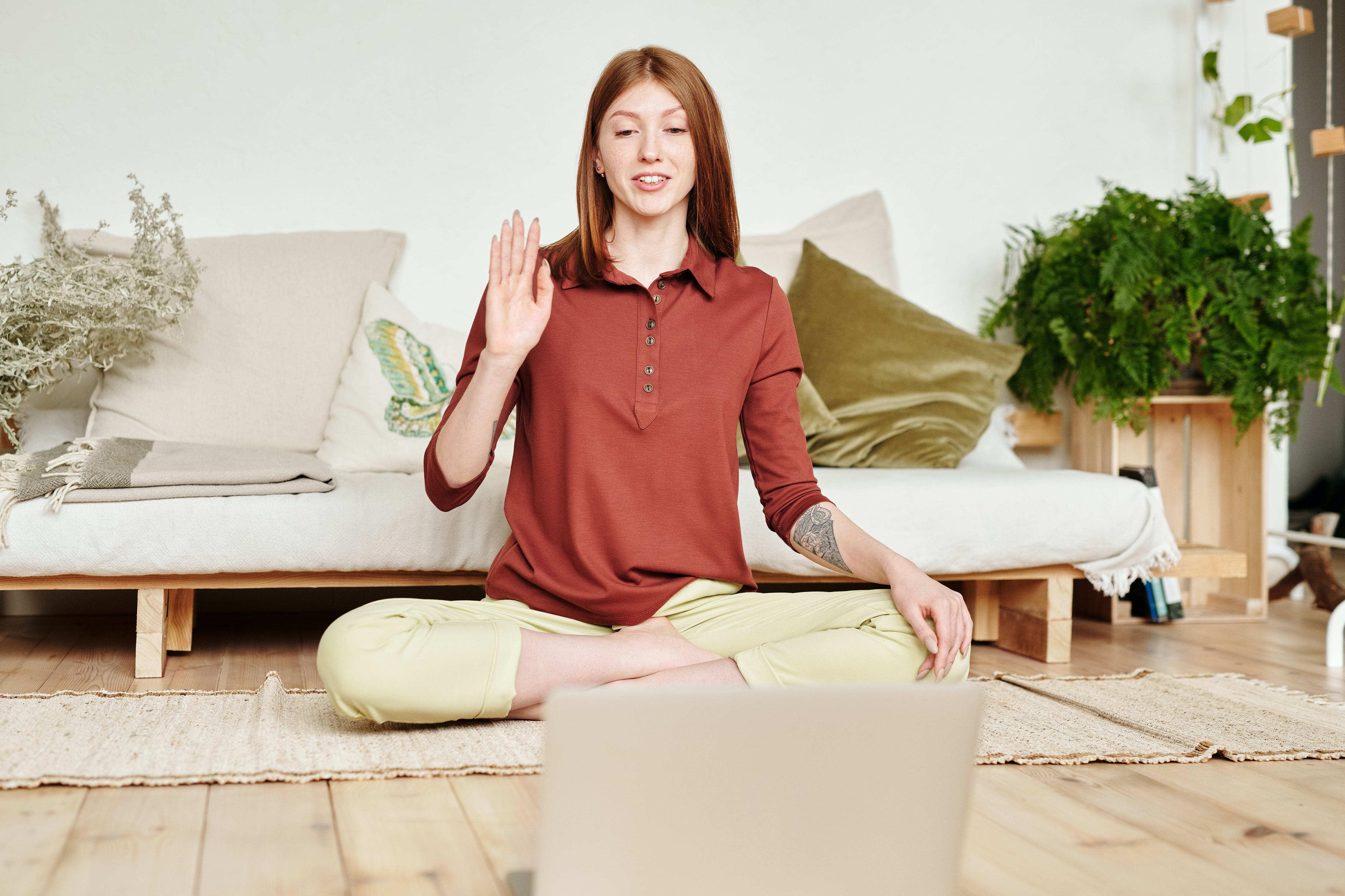 Woman sitting in cross-legged yoga position sitting in front of a laptop