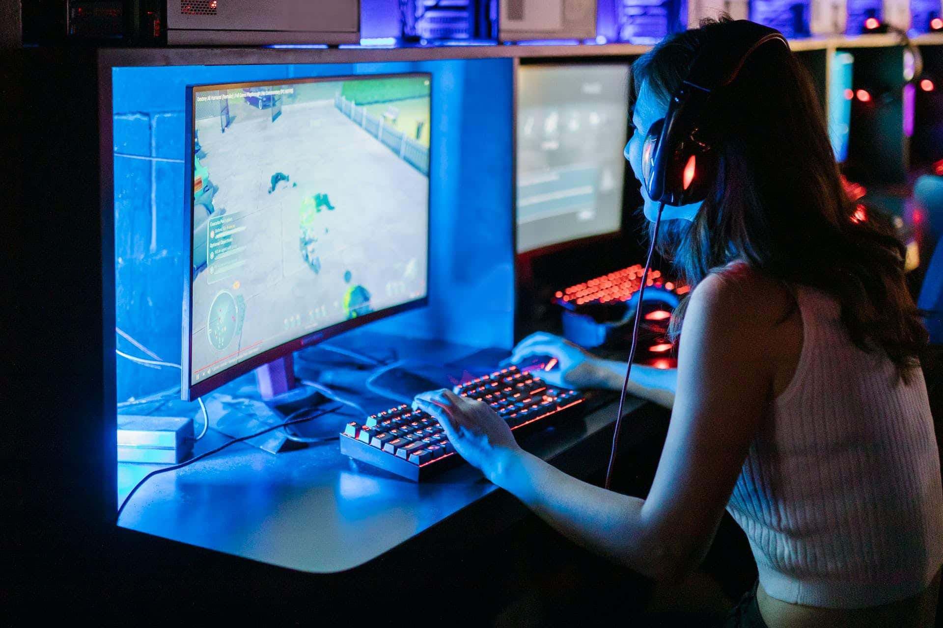 Teen girl excitedly plays a video game on a desktop with neon lights surrounding it