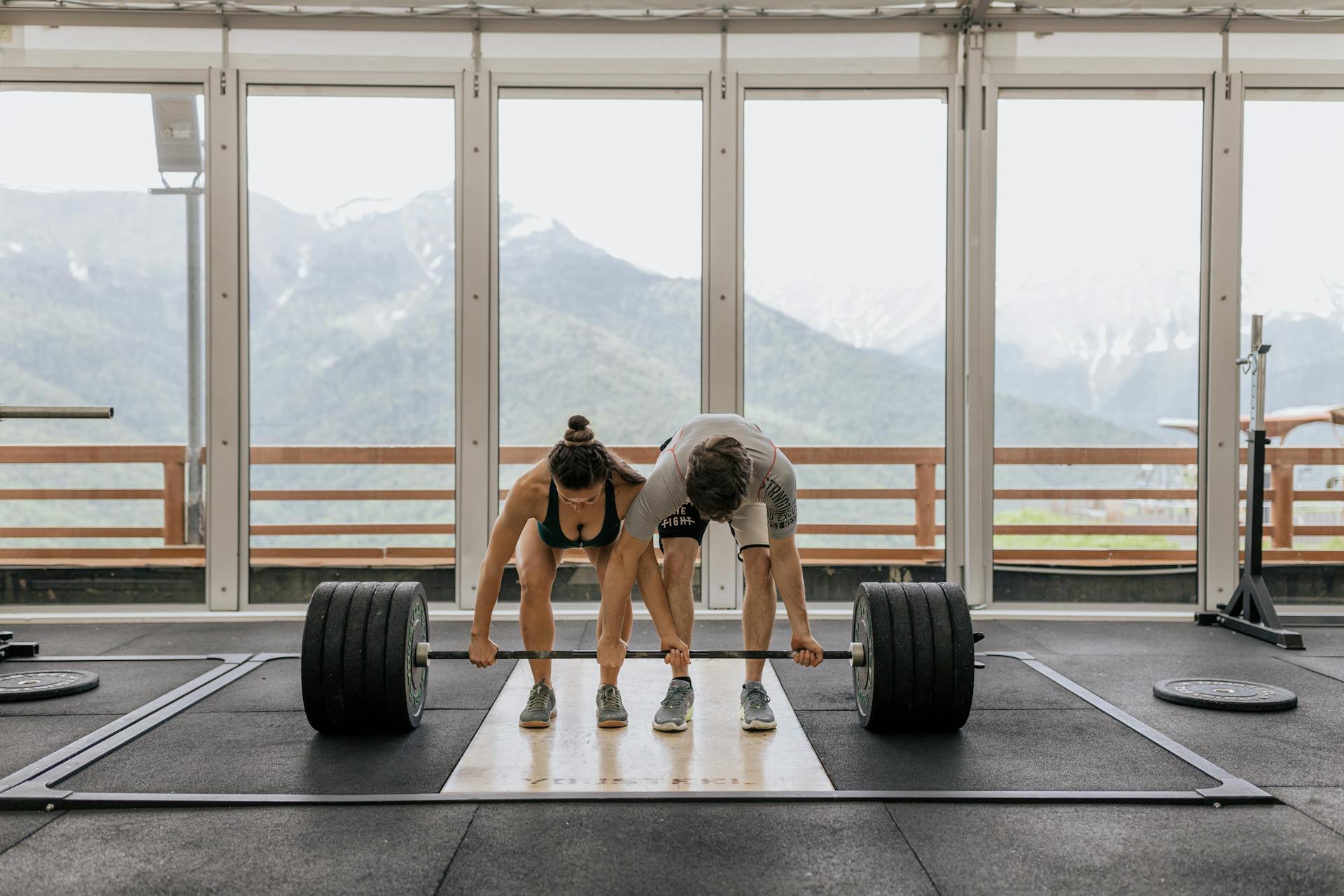 Woman and man prepare to lift a very heavy barbell together.