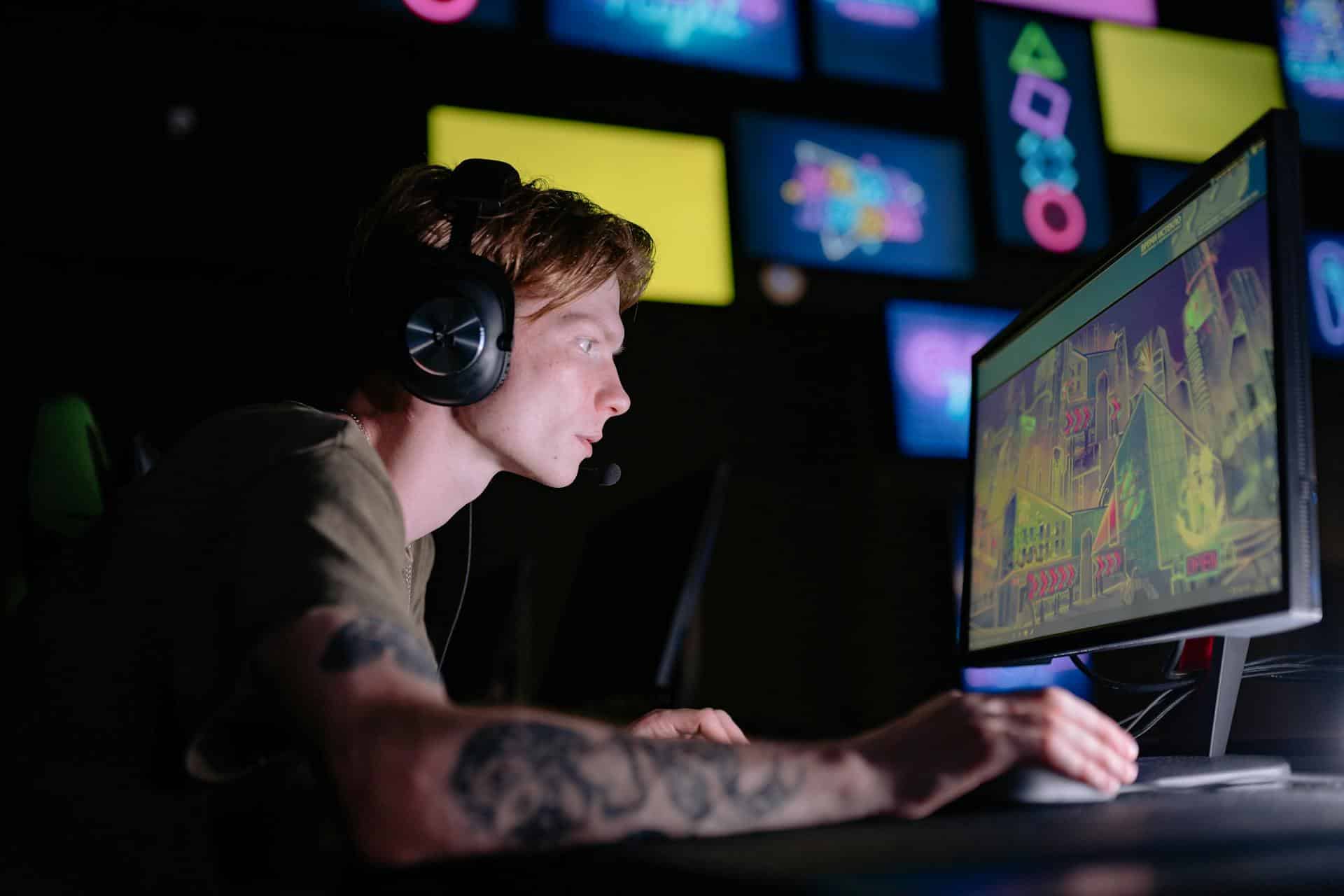 Man wearing headphones stares intently at computer game.