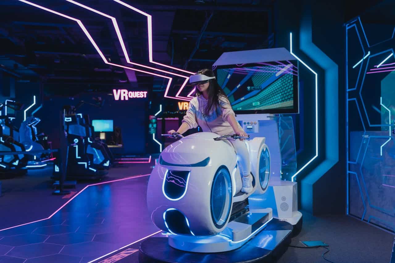 Girl riding a futuristic motorbike simulator wears a VR headset.