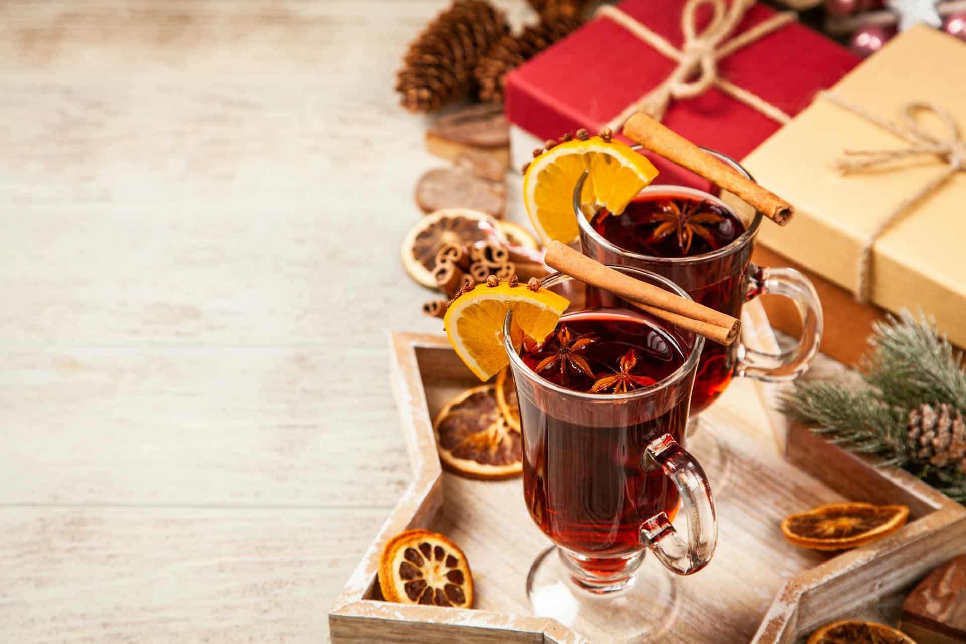 A pair of cups of spiced apple cider with slices of orange on a star shaped tray.