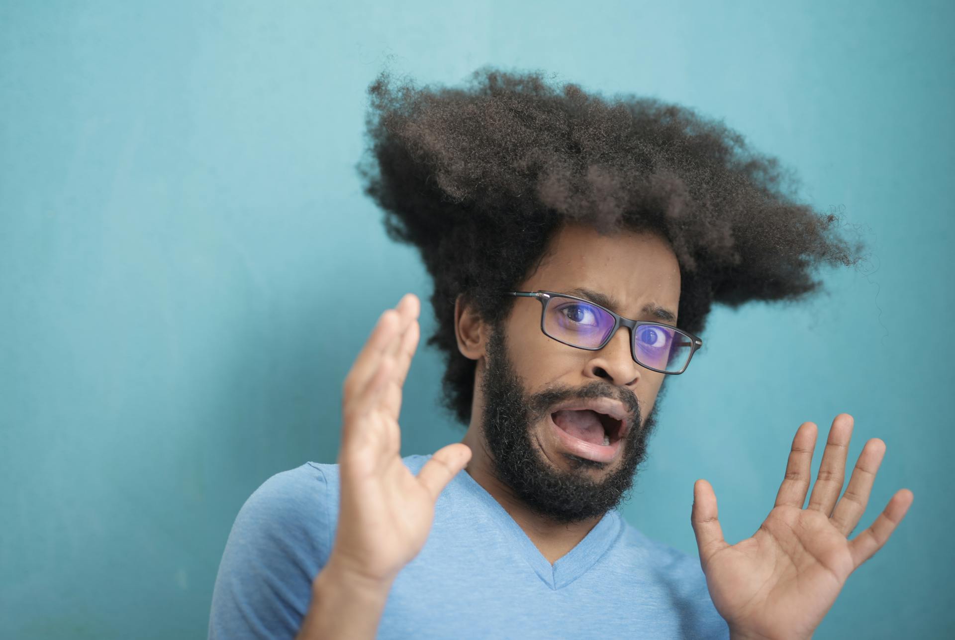 Man with hair sticking straight up looks at the camera with fear.