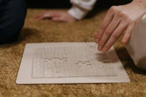Close-up of a clear, imageless, mostly complete puzzle as someone places another clear puzzle piece.