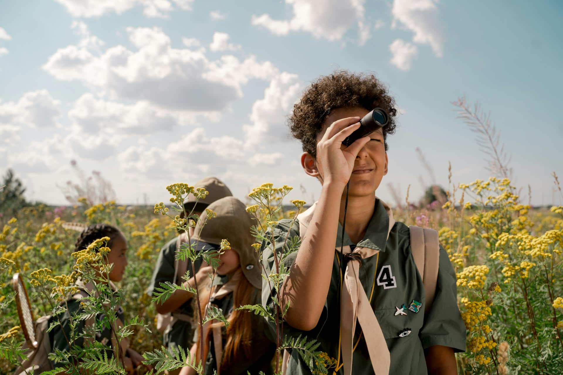 A set of Boy Scouts trooping through a field on an adventure.