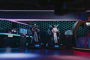 Two people in full VR gear look like they are flying with metal wings.