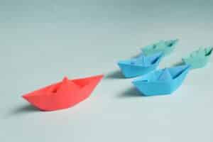 A large origami boat leads several smaller boats