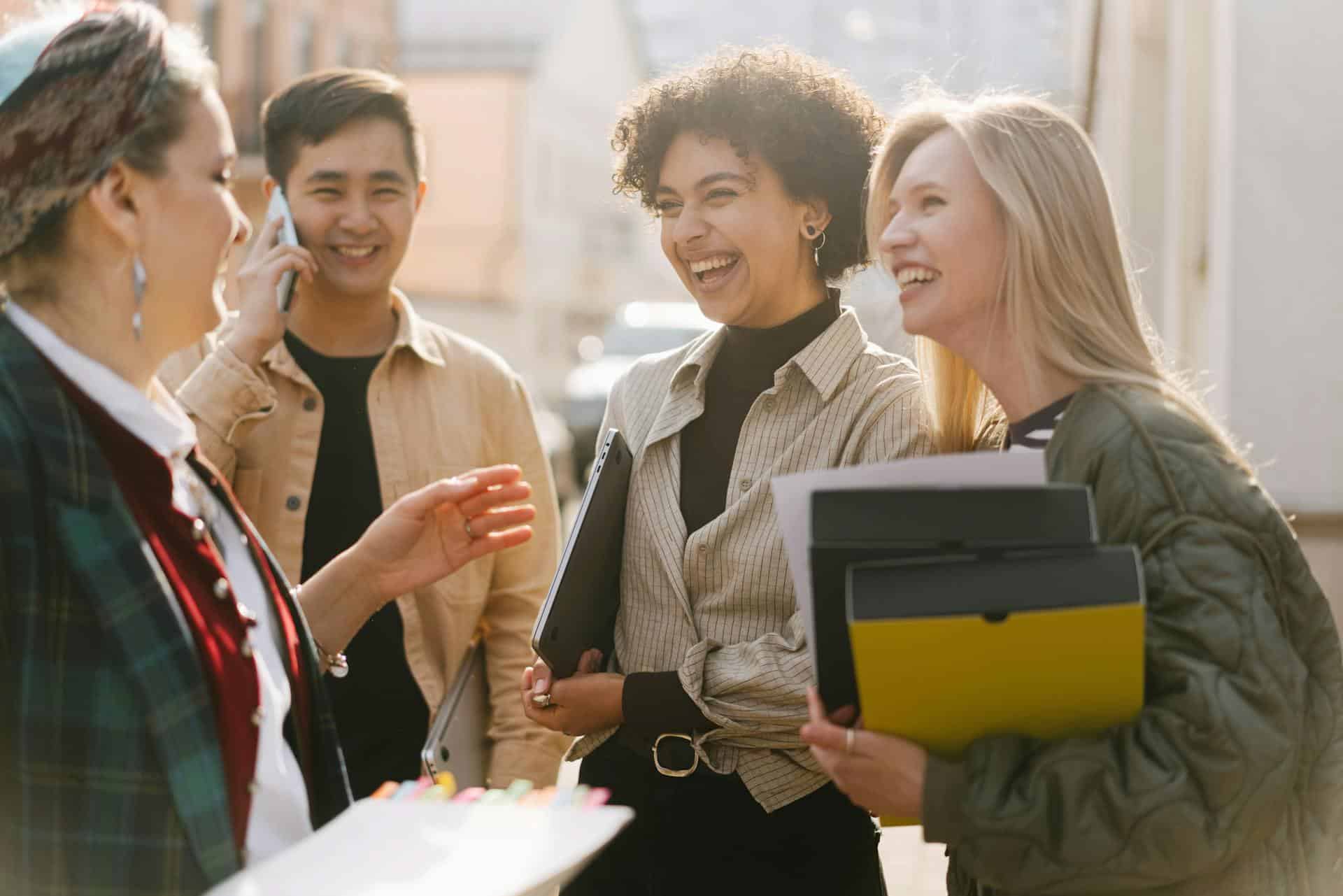 Three women and one man smile while discussing business