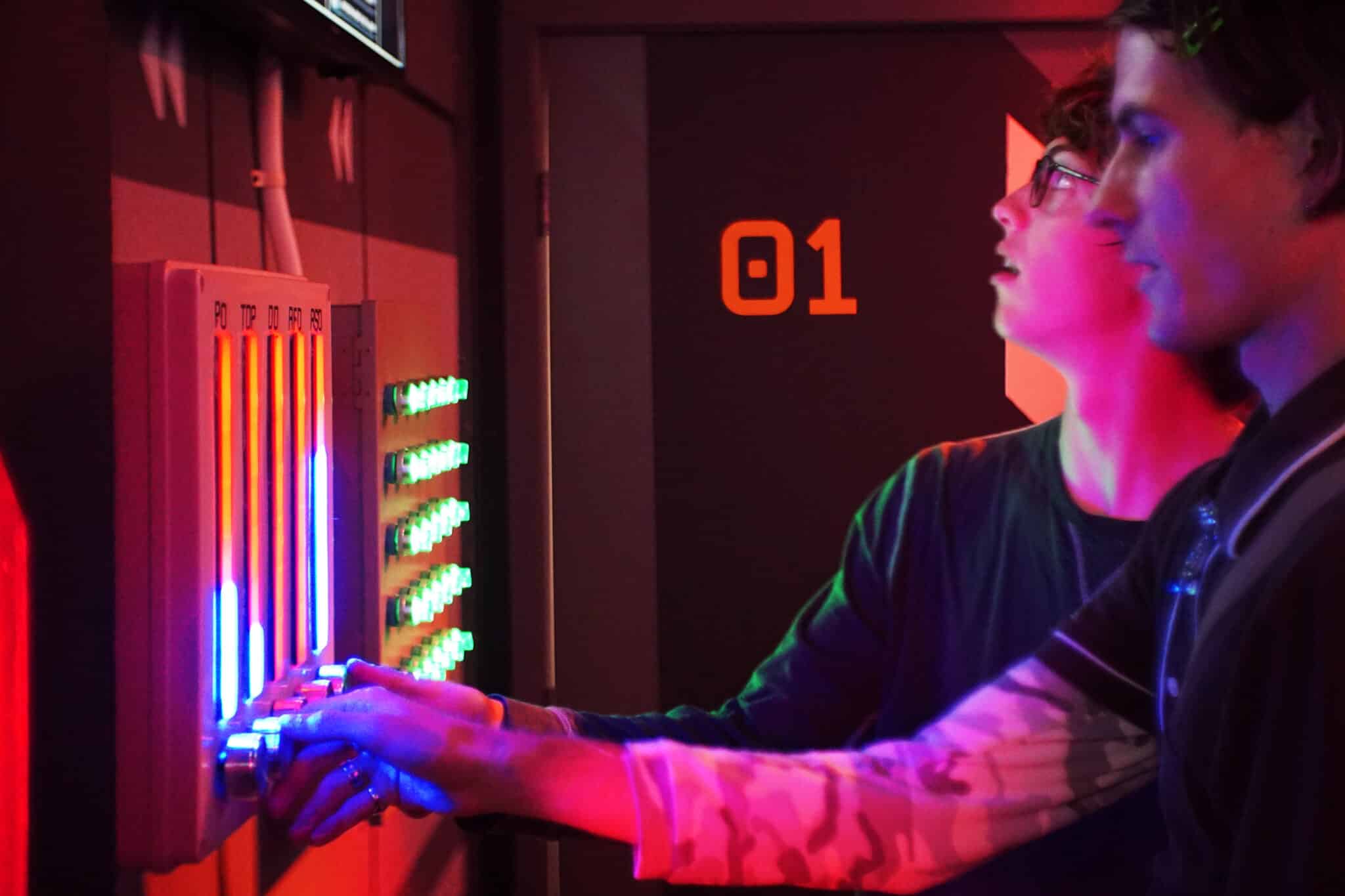 Two players examine Lola 2 Mars escape room's drill settings.