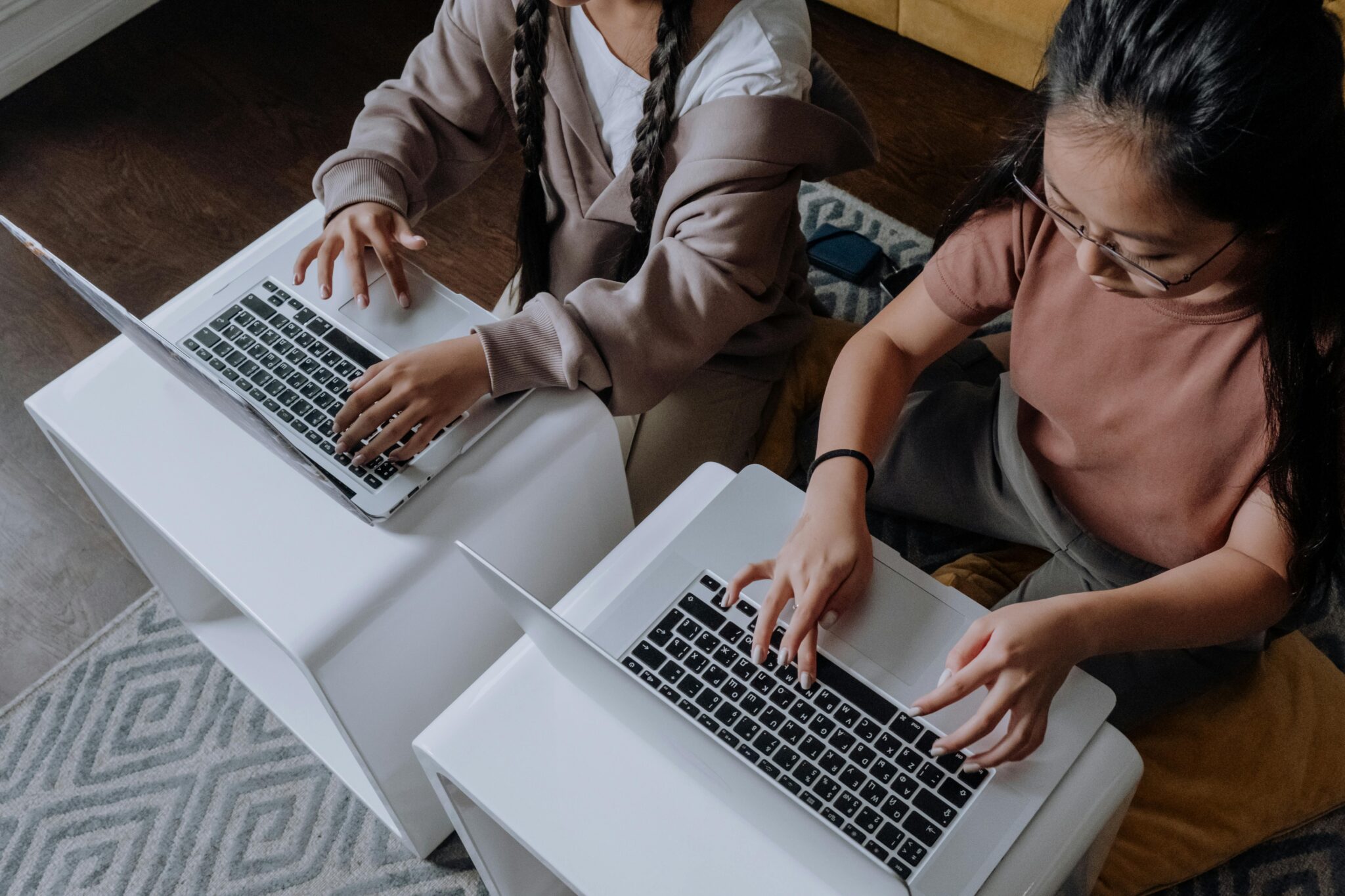 Women typing on laptops while sitting on the floor