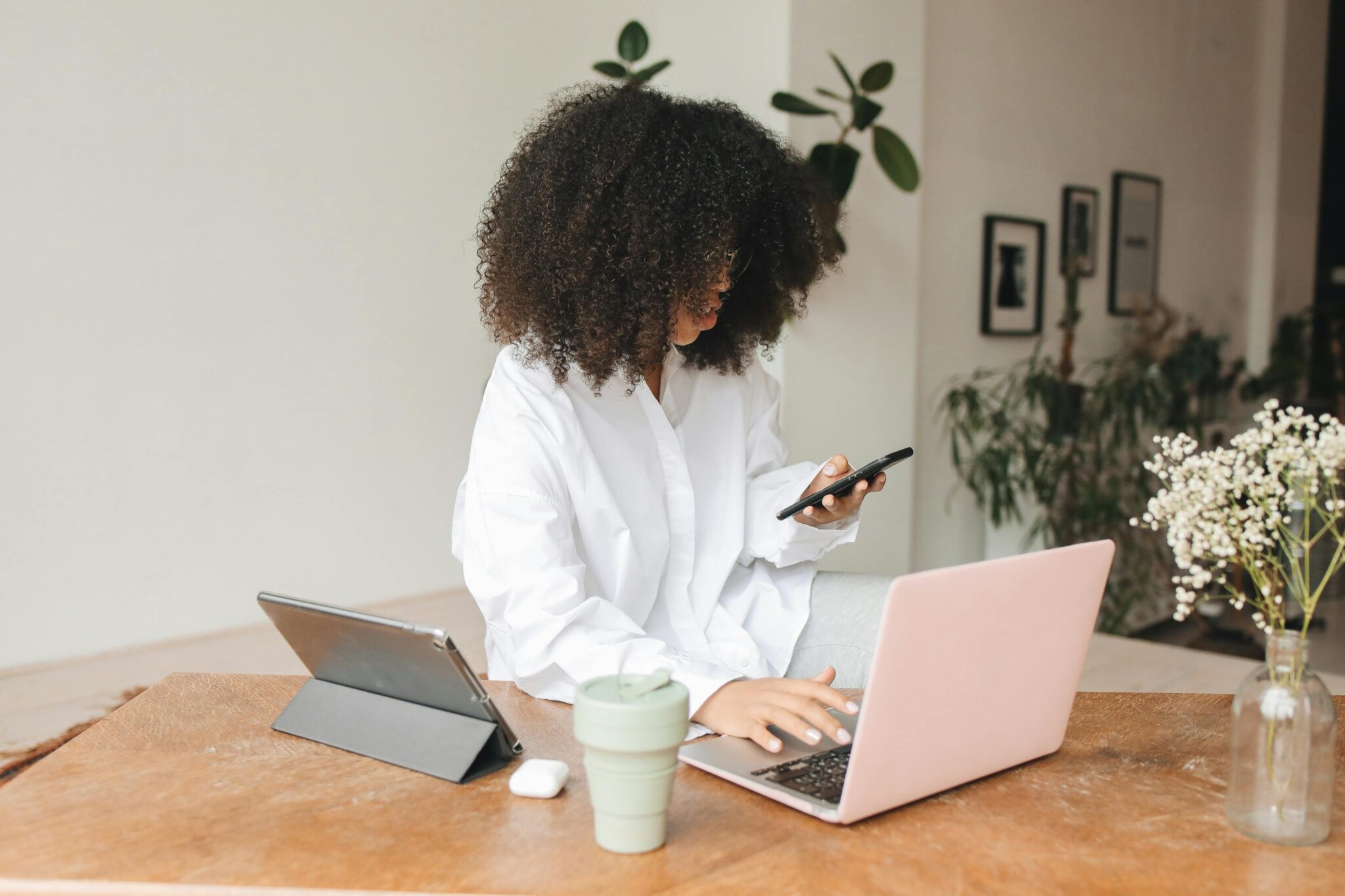 woman on her phone with her laptops at her desk