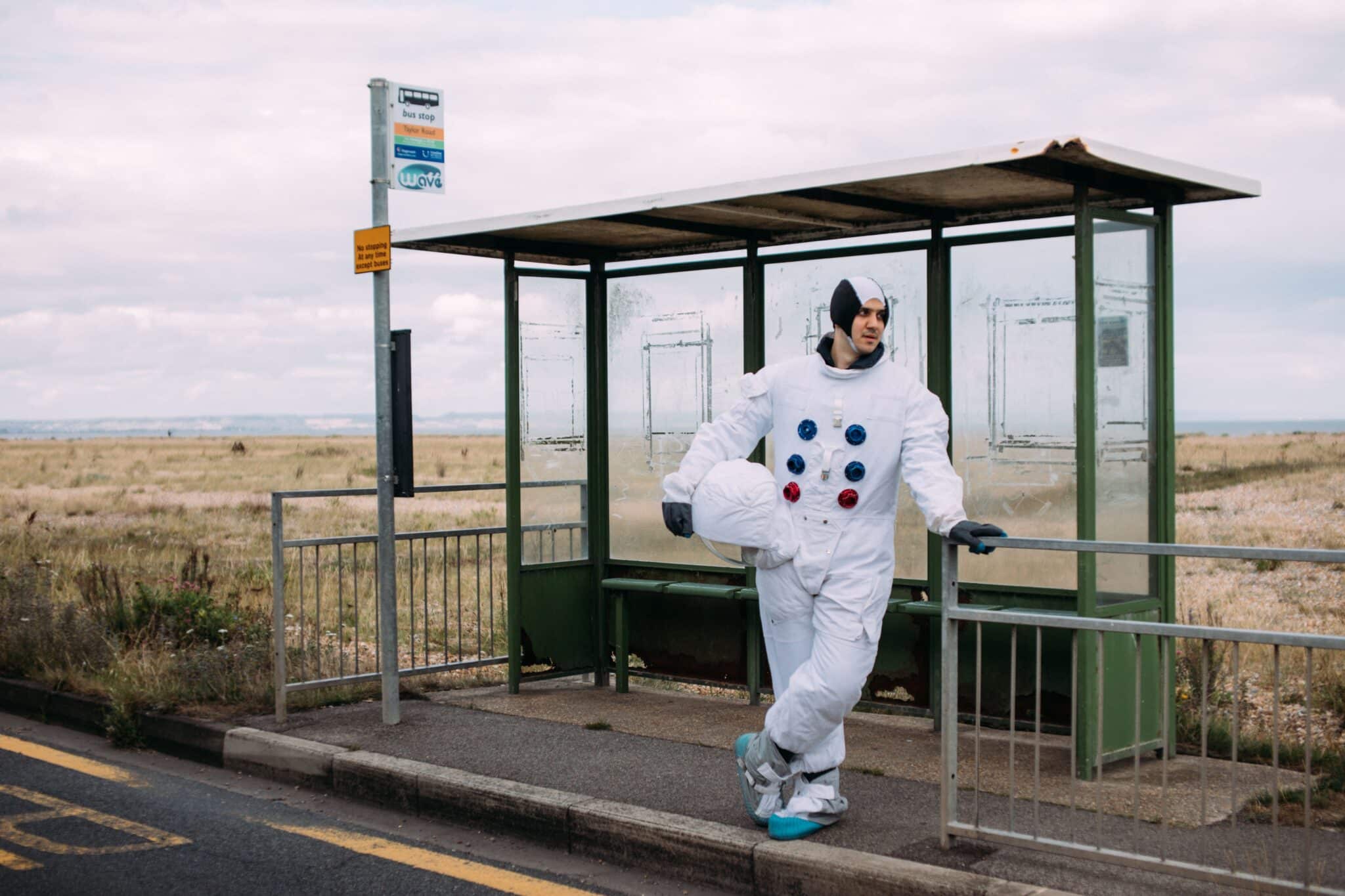 Person wearing an astronaut costume standing at a bus stop