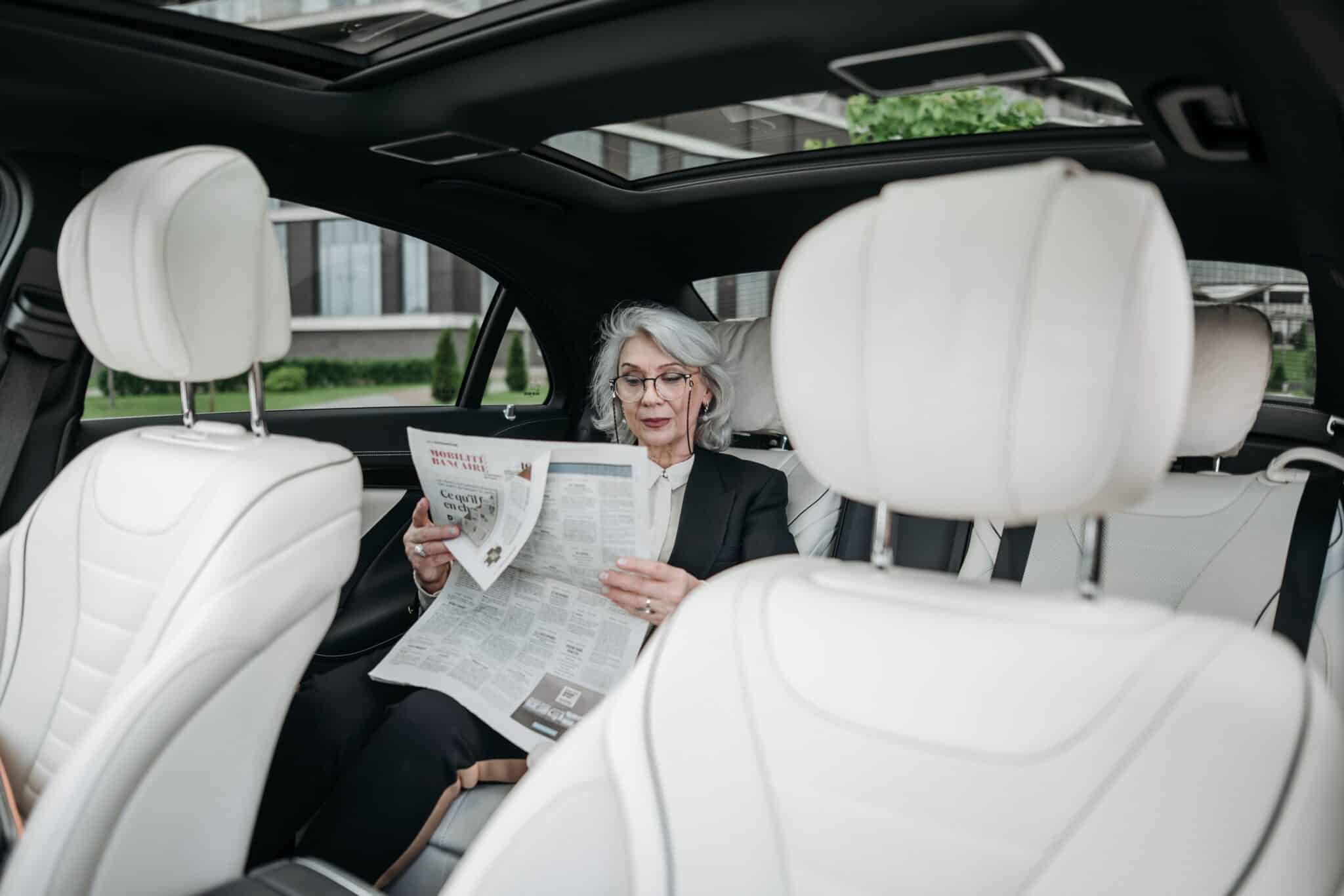 Woman reading newspaper alone in the back seat of a car